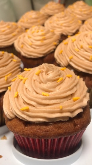 A dozen cupcakes, warm in tone with piped icing and little yellow lightning bolt sprinkles